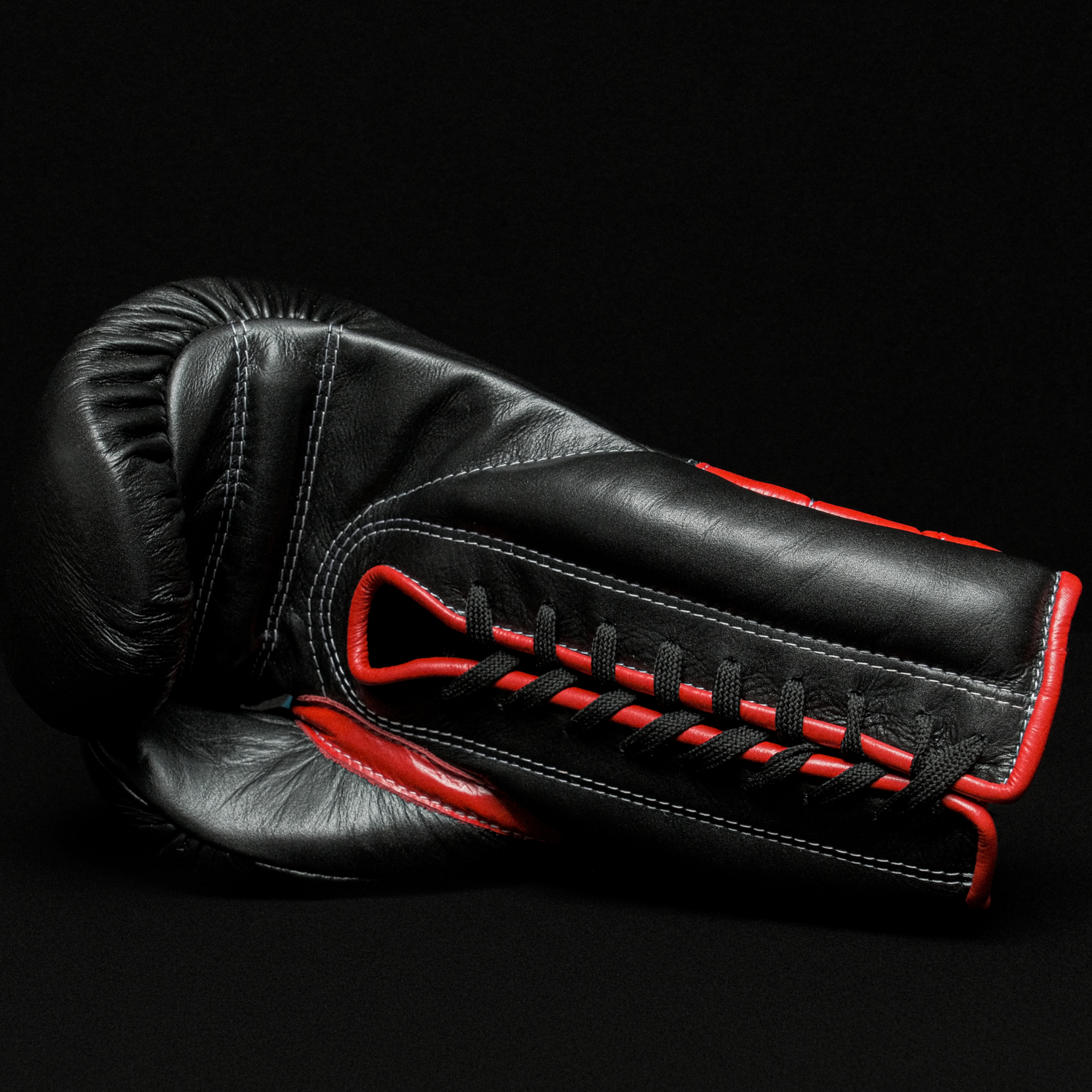 Black boxing glove with red details on a black background.