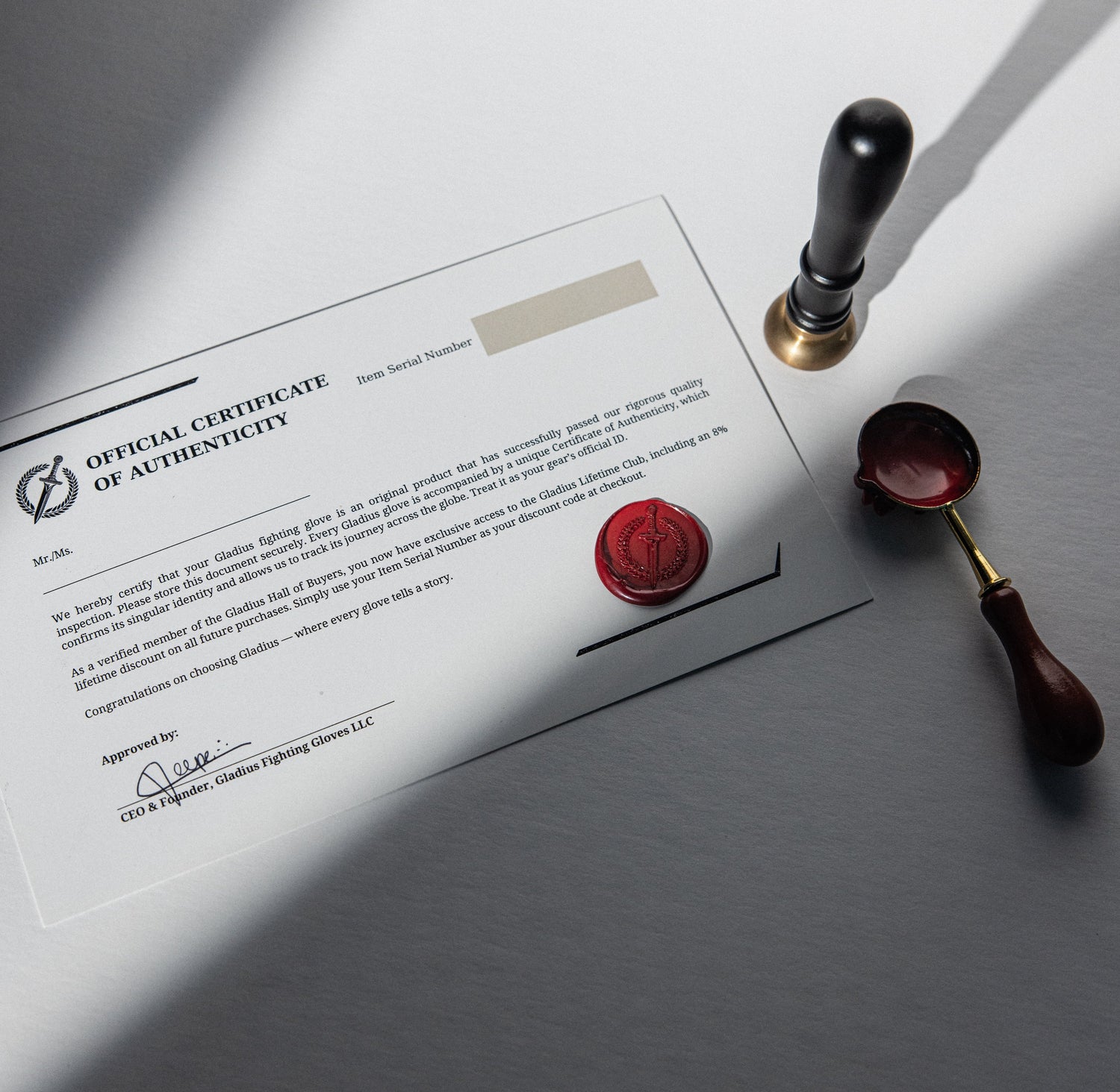 Certificate of authenticity with a red wax seal and sealing tool on a gray surface.