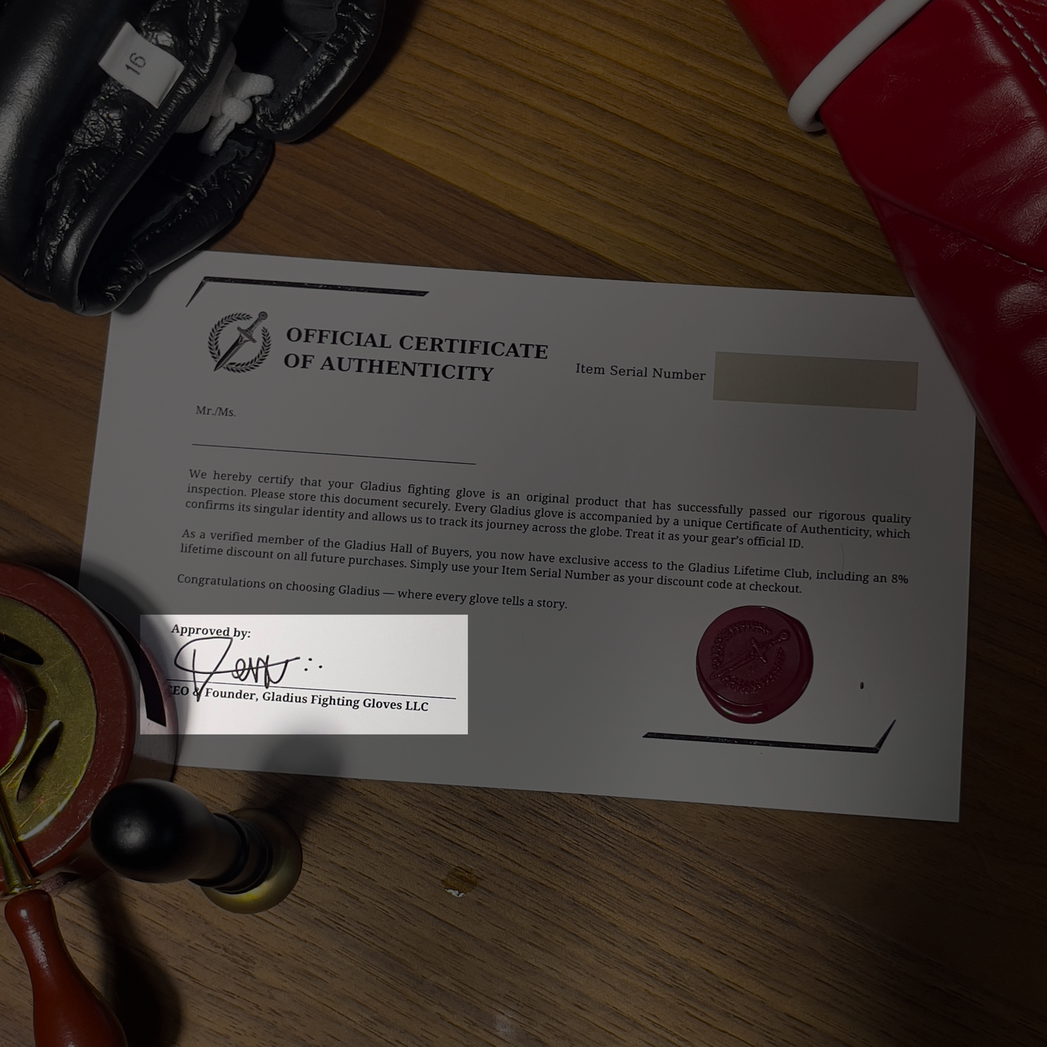 Official Certificate of Authenticity for Gladwin Fighting Gloves on a wooden surface with gloves and a highlight in the founders signature.