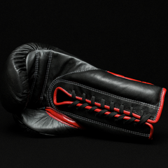 Black boxing glove with red details on a black background.