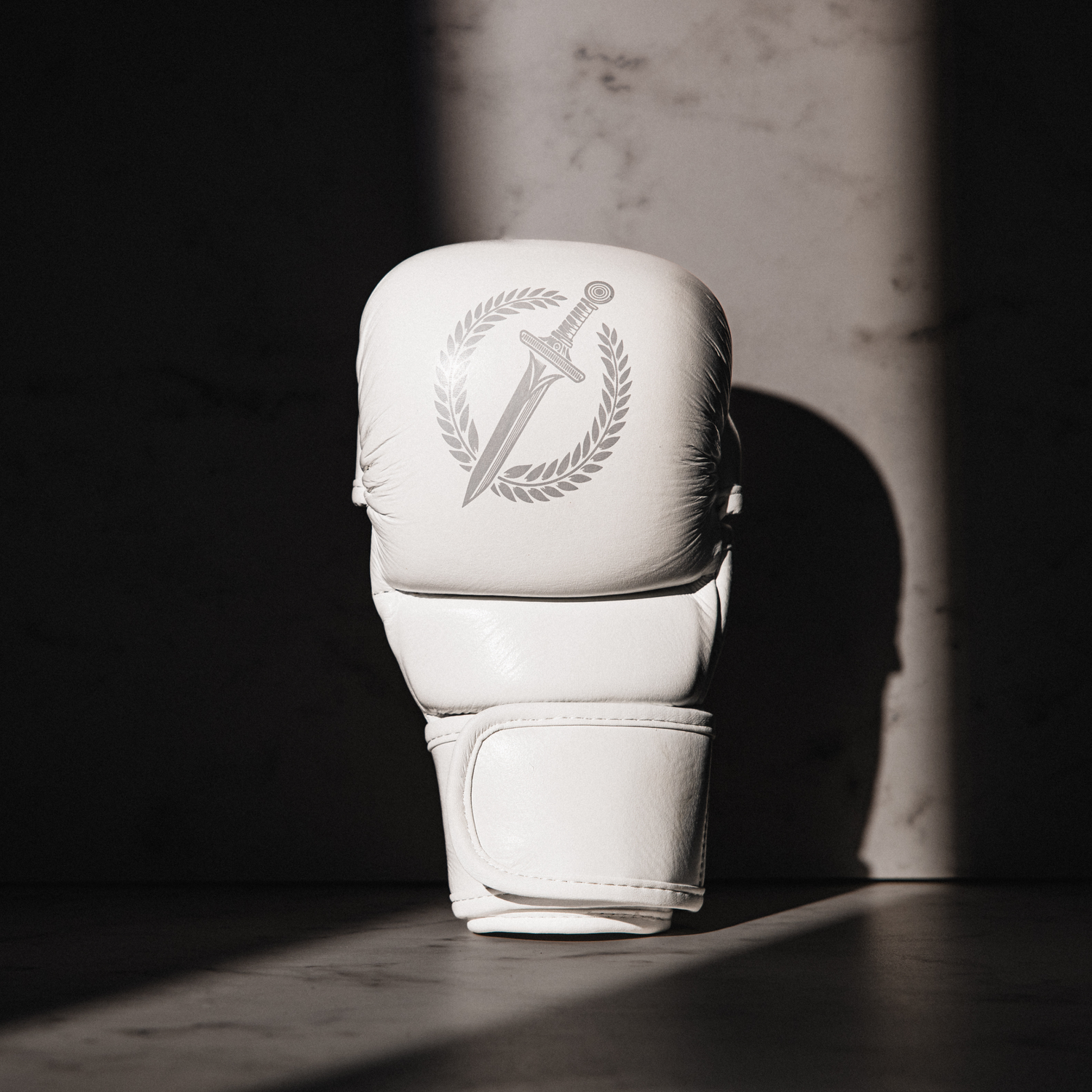 White MMA glove with a logo on a dark background
