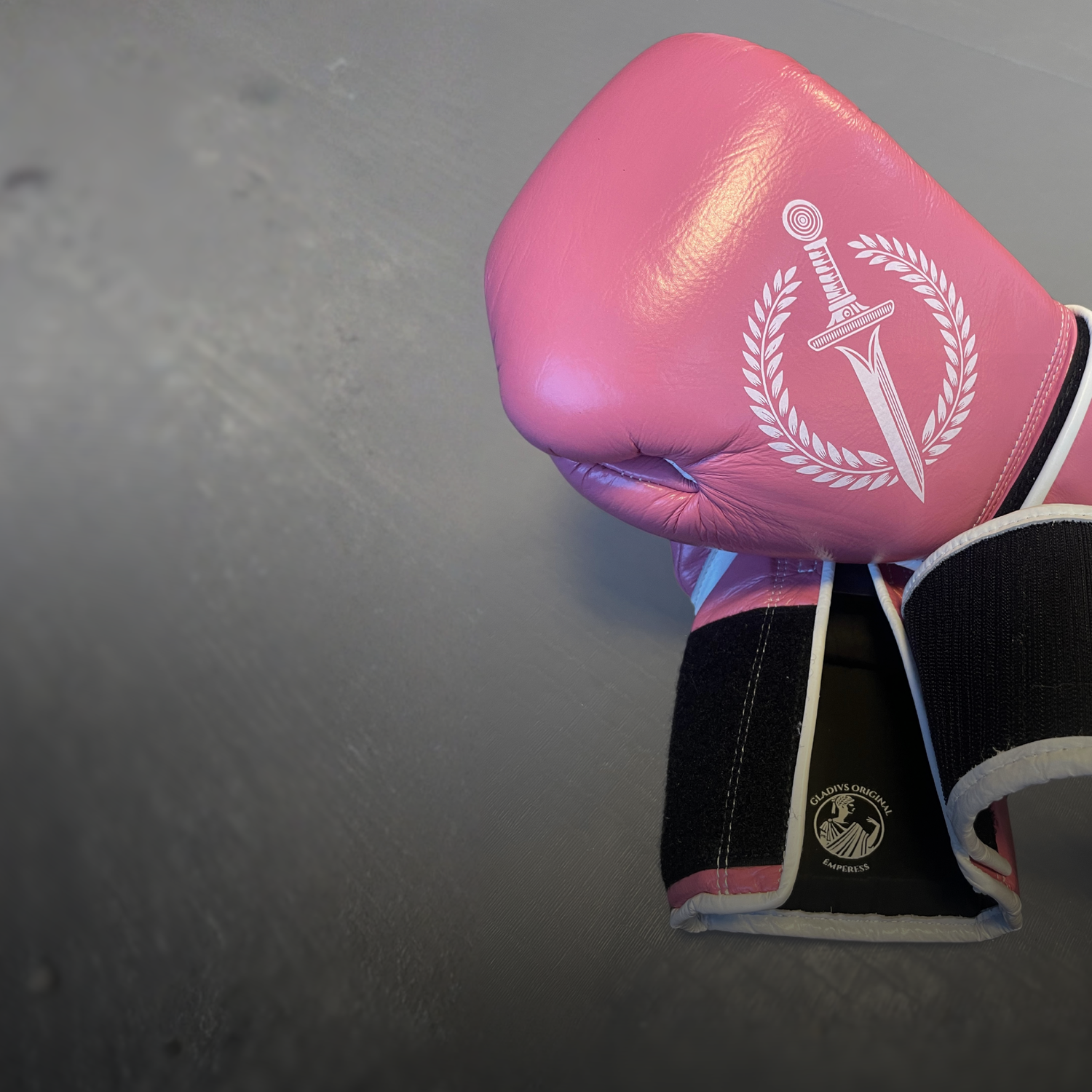 Pink boxing glove with a logo on a gray background.