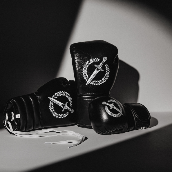 Black boxing gloves with a logo on a gray surface