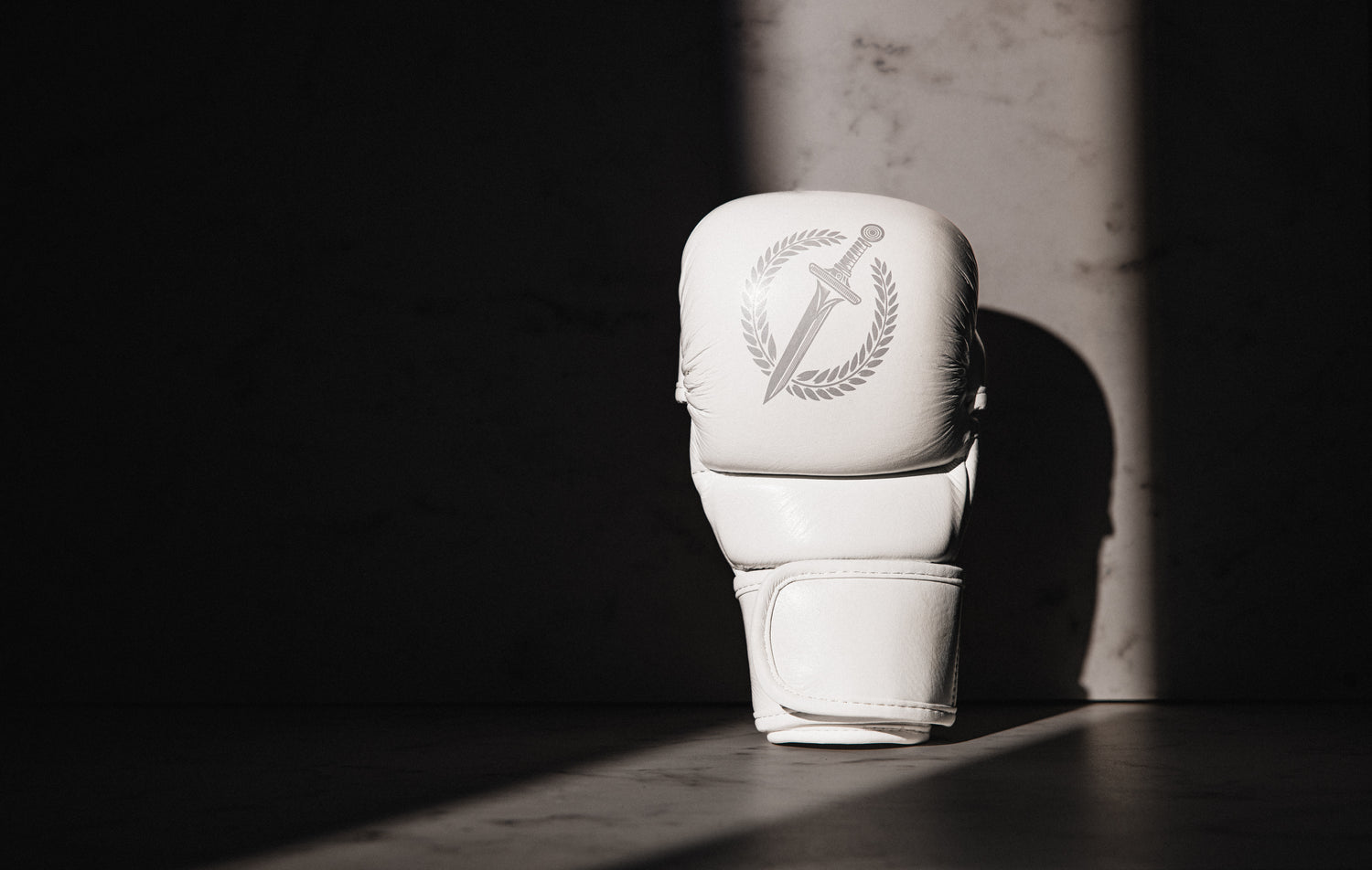 White MMA glove with a logo on a dark background